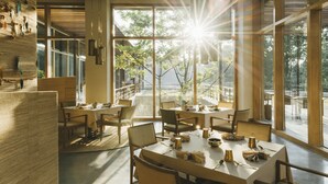 A modern dining area with large windows, natural light, and a view of the outdoors. - Six Senses Vana - A Wellness Retreat (Dehradun)