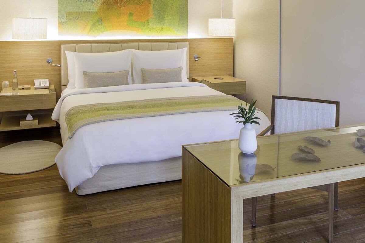 Una habitación de hotel moderna con una cama, mesitas de noche, un escritorio y un ventilador de techo.