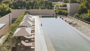 A rooftop pool area with lounge chairs and umbrellas, surrounded by greenery and modern architecture. - Six Senses Vana - A Wellness Retreat (Dehradun)