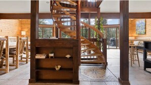 Un intérieur en bois avec un escalier en colimaçon, des meubles en bois et de grandes fenêtres.