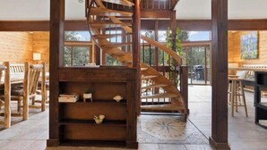 A wooden interior with a spiral staircase, wooden furniture, and large windows. - Westwood Chalet in The Pines with Hot Tub (Woodland Park)