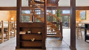A wooden interior with a spiral staircase, wooden furniture, and large windows. - Westwood Chalet in The Pines with Hot Tub (Woodland Park)