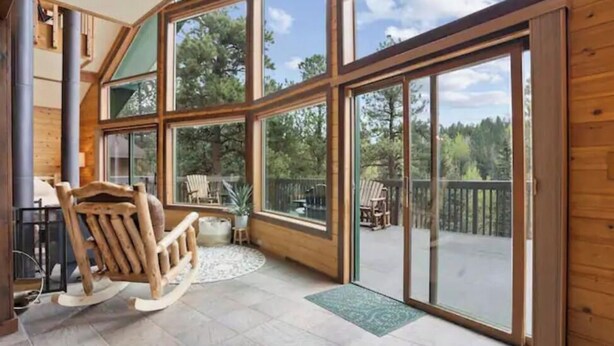 A spacious room with large windows, a wooden rocking chair, and a view of the outdoors.