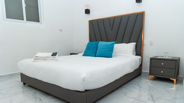 A modern bedroom with a large bed, a nightstand, and a bedside table.
