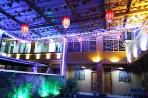 Un edificio tradicional de varios niveles, con fachada de madera y faroles rojos.