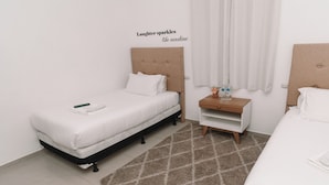 Habitación de hotel ordenada con una cama, una mesita de noche con lámpara y una decoración en la pared.