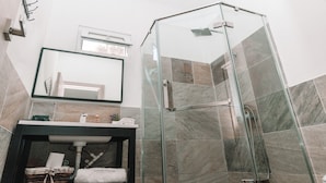 Un baño moderno con cabina de ducha de vidrio, un lavabo con tocador y un espejo sobre él.
