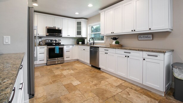 A kitchen with white cabinets, stainless steel appliances, and a granite countertop.