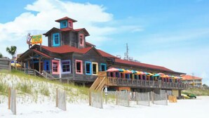 A beachside wooden building with multiple colorful windows and a red roof. - FREE DAILY BEACH SERVICE!!!, GULFVIEW,GROUND FLOOR (Miramar Beach)