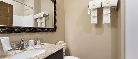 A bathroom with a sink, mirror, towel rack, toilet, and a door.