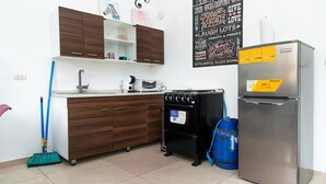 Una cocina compacta con horno empotrado, refrigerador y estufa a gas.