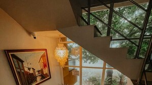 Un interior moderno con una escalera, una araña y un cuadro en la pared.