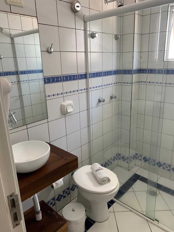 Un baño con lavamanos blanco, inodoro y cabina de ducha de vidrio.