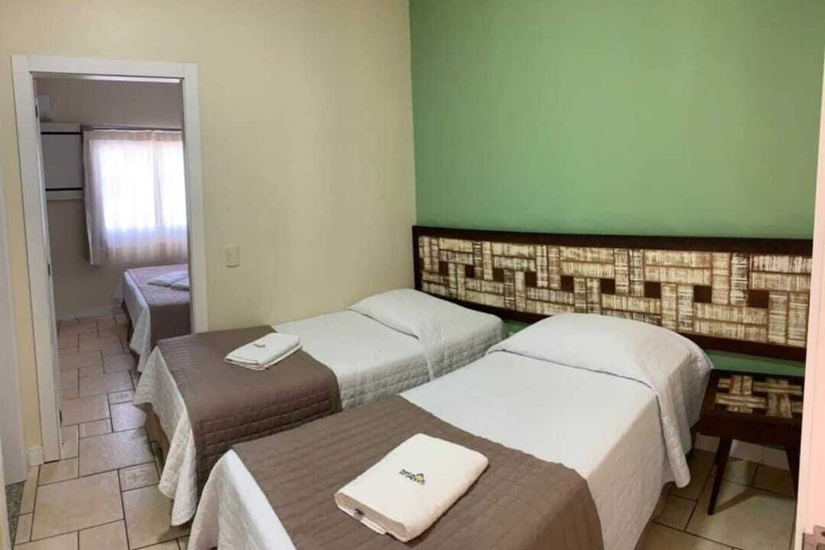 Ein Hotelzimmer mit zwei Einzelbetten, einem kleinen Tisch und einem Kopfende mit Muster.