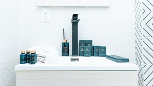 Een badkamermeubel met een wit aanrechtblad, een zwarte kraan en diverse toiletartikelen, waaronder flessen en dozen.