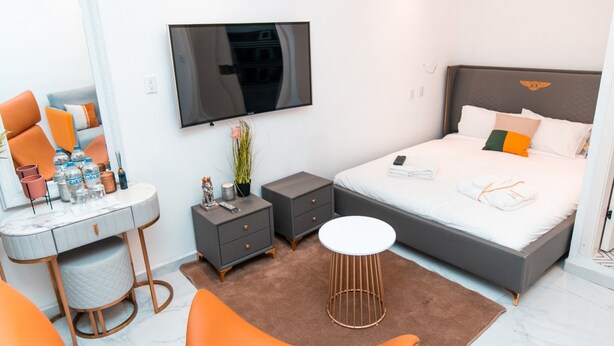 Een moderne hotelkamer met een groot bed, een flatscreen televisie, een kaptafel met spiegel en een kleine ronde tafel.