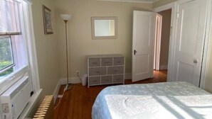 Quarto com cama, cómoda, radiador e janela.
