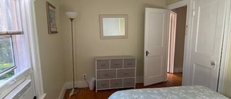 A bedroom with a bed, a dresser, a radiator, and a window.