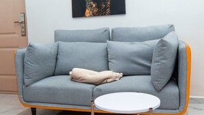 A grey sofa with a beige throw blanket, a small white table, and a door in the background.