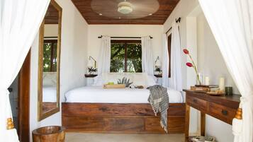 Un dormitorio con una cama de madera, una mesita de noche, un espejo y una ventana con cortinas.