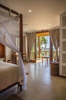Un dormitorio con una cama con dosel, un escritorio de madera y vistas al exterior.