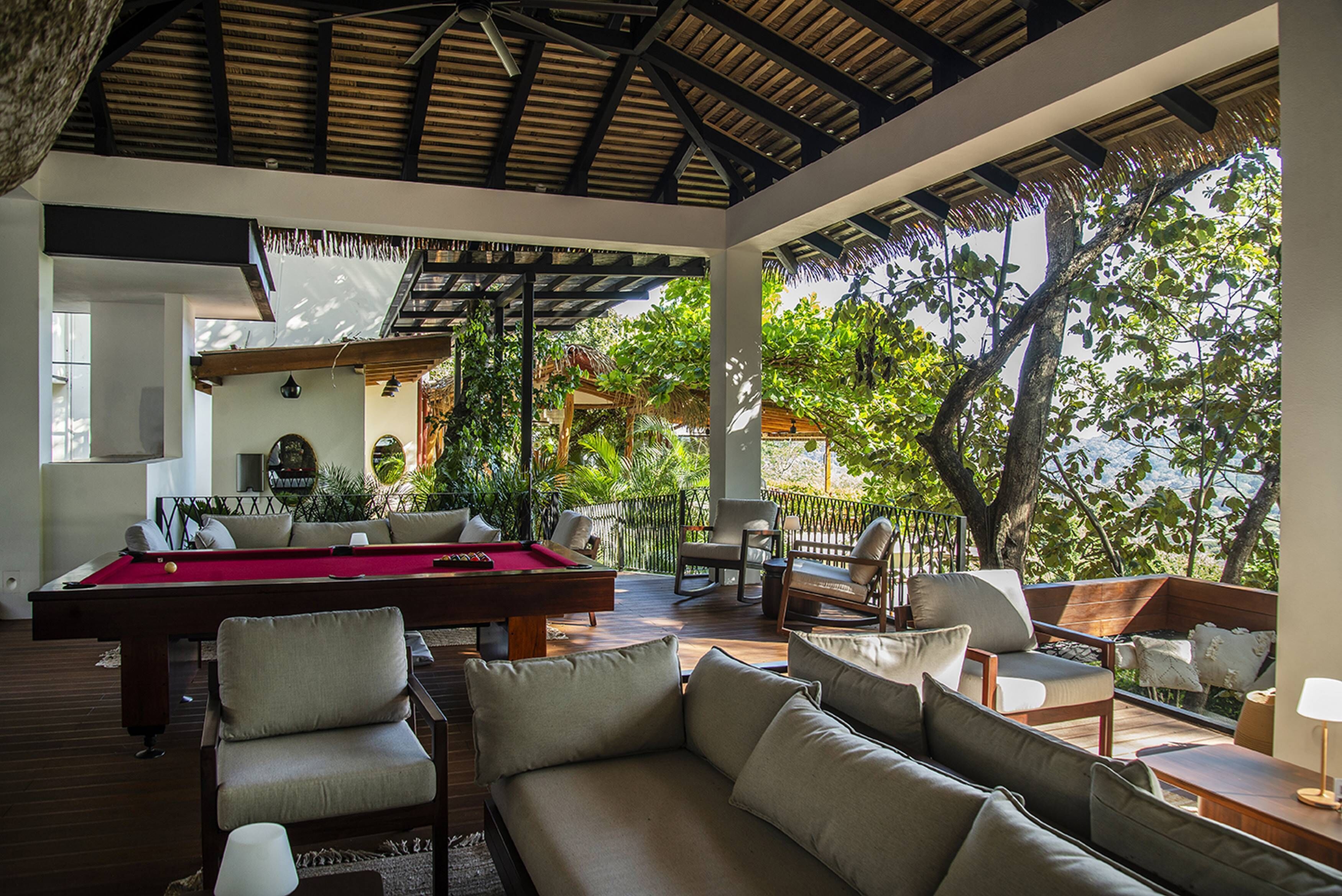 Zona de piscina con mesa de billar, asientos y vistas al exterior.