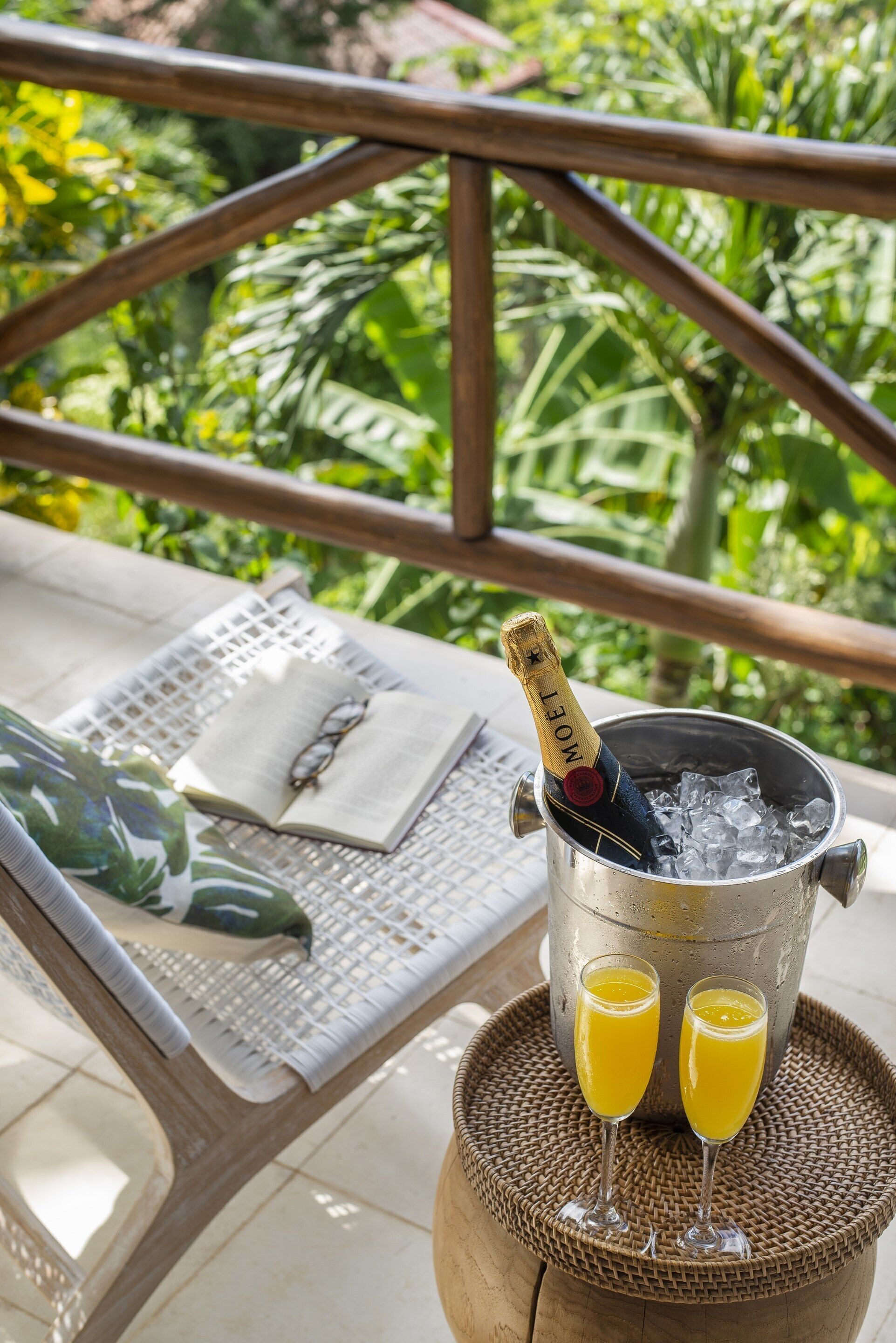 A table with a bottle of champagne, two glasses of orange juice, and a book.
