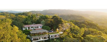 Un resort con varias edificaciones rodeado de exuberante vegetación y colinas.