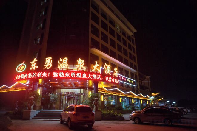 A hotel with illuminated signage and a car parked in front.