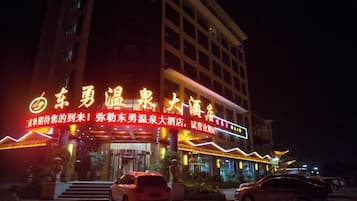 A hotel with illuminated signage and a car parked in front.