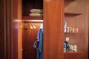 A wooden closet with hanging clothes and shelves containing toiletries. - Dongyong Hot Spring Hotel (Mile)