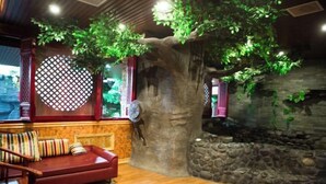 Une pièce chaleureuse avec une grande sculpture en forme d’arbre, un canapé rouge et un plancher en bois.