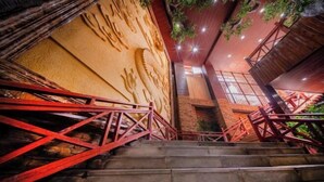 Un escalier avec des rampes rouges menant à un bâtiment dont la façade est revêtue d’un matériau texturé et qui possède une fenêtre.