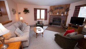 A cozy living room with a fireplace, a sofa, a chair, and a television. - Ski-in/Ski-out | FREE ACCESS Spring House Pool (Ludlow)