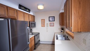 A compact kitchen with wooden cabinets, a stainless steel refrigerator, a microwave, and a sink. - Ski-in/Ski-out | FREE ACCESS Spring House Pool (Ludlow)