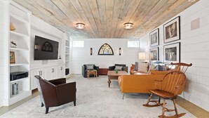 Un salón acogedor con chimenea, un sofá, un sillón mecedor y un televisor en la pared.