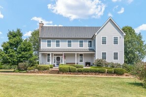 A two-story house with a front porch, a chimney, and a well-maintained lawn.