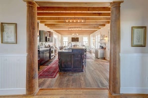 Una cocina amplia con vigas de madera, una isla central y vistas a habitaciones contiguas.
