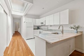 A modern kitchen with white cabinetry, a marble countertop, and a built-in oven.