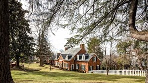 A row of brick houses with a white picket fence, surrounded by trees and a grassy yard. - Hoos` Homestead | Historic UVA area home (Charlottesville)