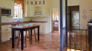 A kitchen with white cabinets, a wooden table, and a tiled floor. - Hoos` Homestead | Historic UVA area home (Charlottesville)