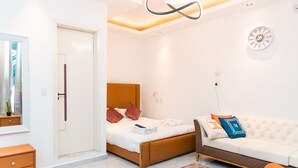 Een moderne slaapkamer met een bed, een witte bank, een klok aan de muur en een deur.