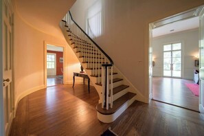 A wooden staircase with a handrail, leading to a room with a door and a window. - Colle | Historic Estate with Pool (Charlottesville)