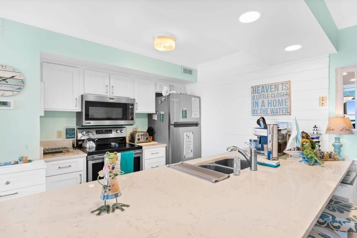 A modern kitchen with white cabinets, stainless steel appliances, and a marble countertop.