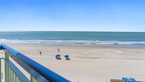 Vista sulla spiaggia dal balcone, con ringhiera, spiaggia sabbiosa e l'oceano.
