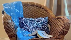 A wicker chair with a blue and white patterned pillow and a blue cloth with text. - Peaceful, Fully Equipped Cabin Near Beach & Town, Certified NWF Wildlife Habitat (Seaview)