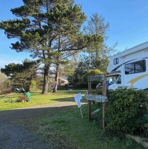 A campground with RVs, a signpost, and a large tree. - Peaceful, Fully Equipped Cabin Near Beach & Town, Certified NWF Wildlife Habitat (Seaview)