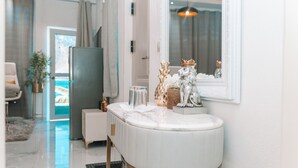 Casa de banho moderna com toucador branco, espelho e objetos decorativos, incluindo uma estátua de leão e um vaso.