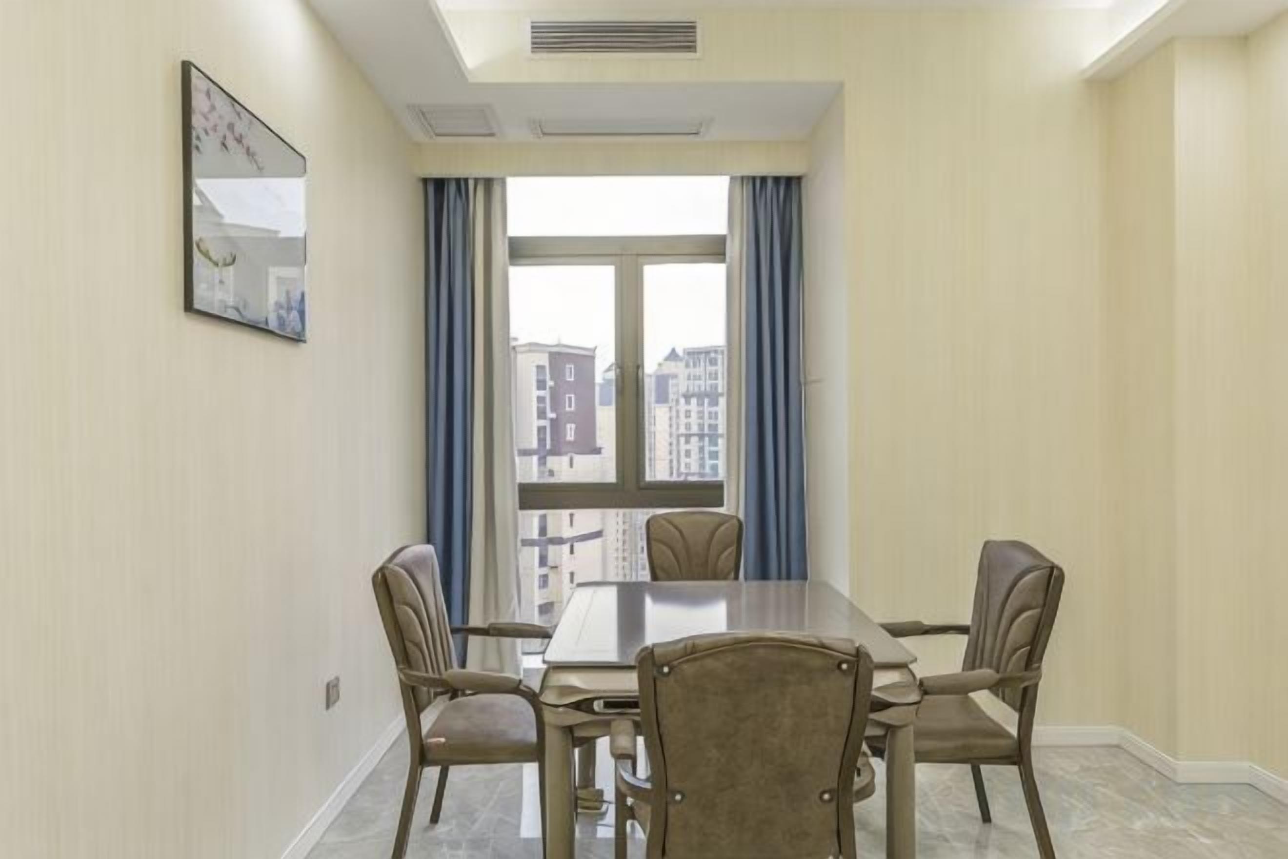 A conference room with a rectangular table, four chairs, a large window with curtains, and a city view.