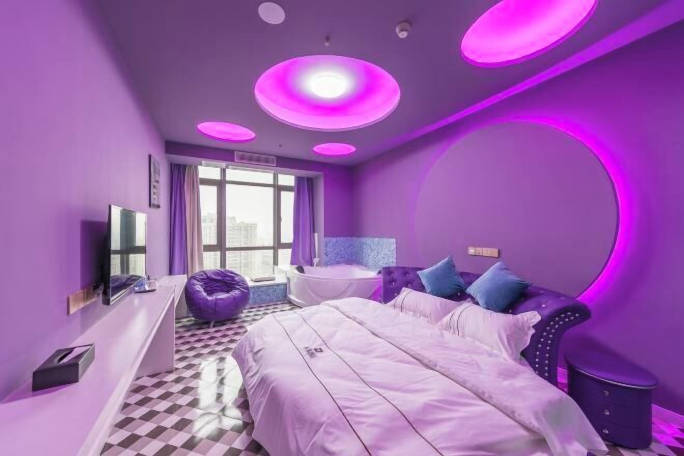 Ein modernes Schlafzimmer mit Bett, Schminktisch, Badewanne und großem Fenster.